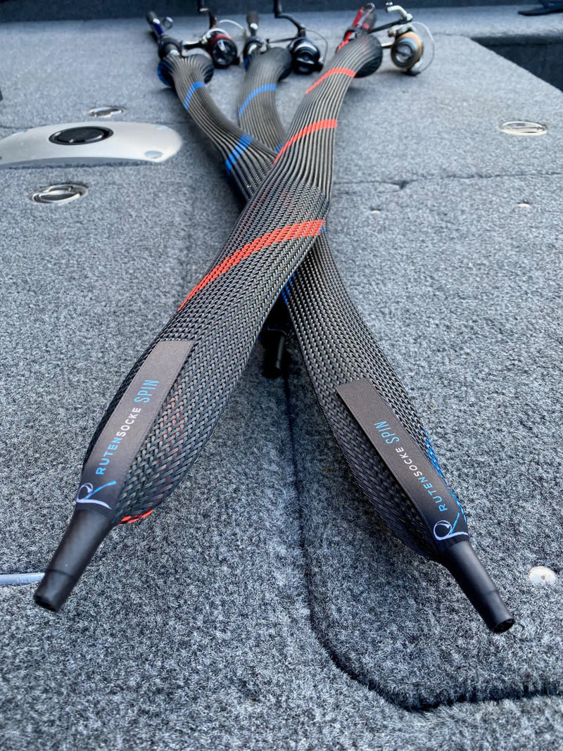 Schwarze gewebte Angelrutenhüllen mit roten und blauen Akzentstreifen, mit der Marke 'rutendo spinn' auf grauen Etiketten.