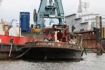 Industrielle Barke mit Graffiti, rote und weiße Rümpfe, Metallstruktur, großer Kranarm.